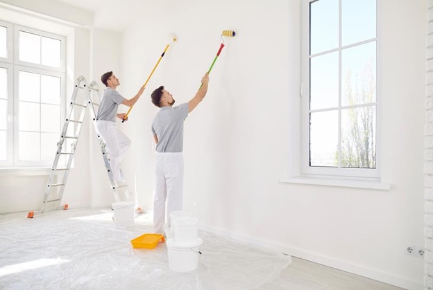 Two men painting walls in a living room.